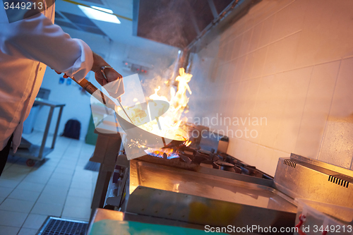 Image of chef in hotel kitchen prepare food with fire