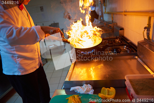 Image of chef in hotel kitchen prepare food with fire