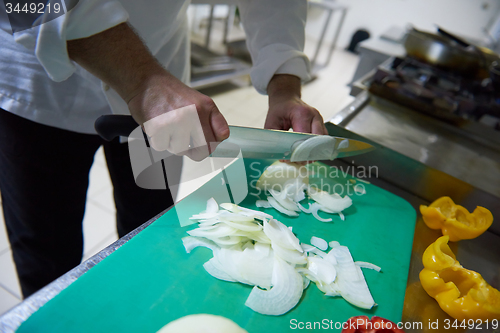 Image of chef in hotel kitchen  slice  vegetables with knife