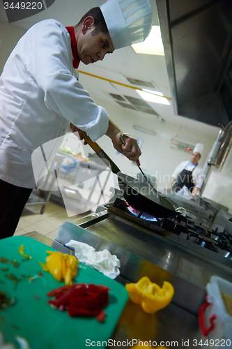 Image of chef in hotel kitchen prepare food with fire