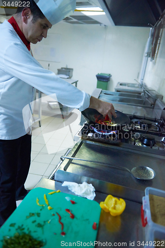 Image of chef in hotel kitchen prepare food with fire