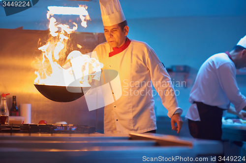 Image of chef in hotel kitchen prepare food with fire