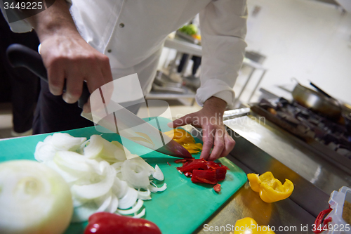 Image of chef in hotel kitchen  slice  vegetables with knife