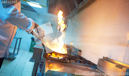 Image of chef in hotel kitchen prepare food with fire