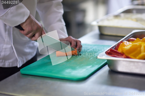 Image of chef in hotel kitchen  slice  vegetables with knife