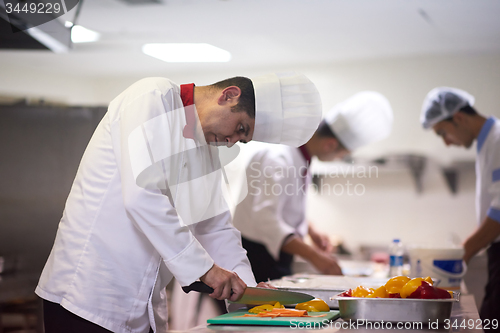 Image of chef in hotel kitchen  slice  vegetables with knife