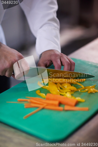 Image of chef in hotel kitchen  slice  vegetables with knife