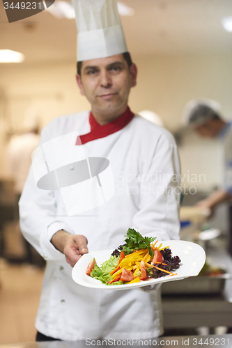 Image of chef in hotel kitchen preparing and decorating food