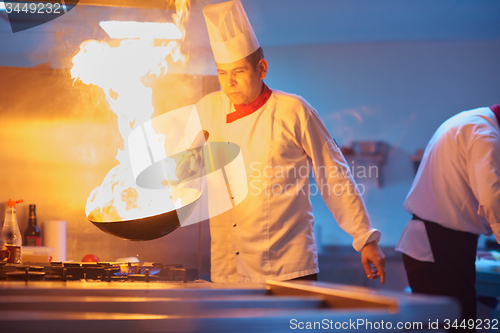 Image of chef in hotel kitchen prepare food with fire