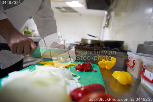 Image of chef in hotel kitchen  slice  vegetables with knife