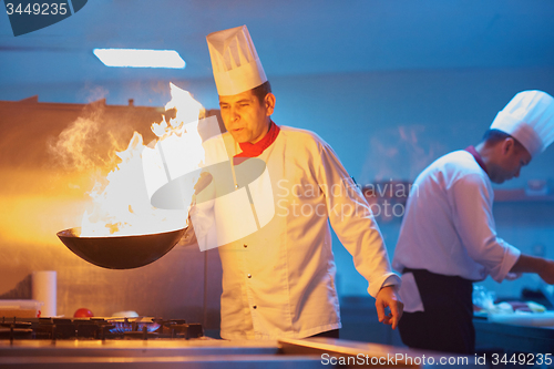 Image of chef in hotel kitchen prepare food with fire