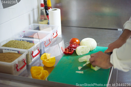 Image of chef in hotel kitchen  slice  vegetables with knife