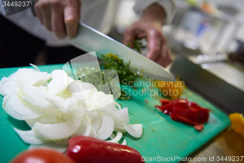 Image of chef in hotel kitchen  slice  vegetables with knife