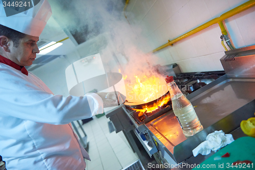 Image of chef in hotel kitchen prepare food with fire