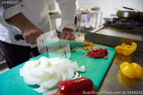 Image of chef in hotel kitchen  slice  vegetables with knife