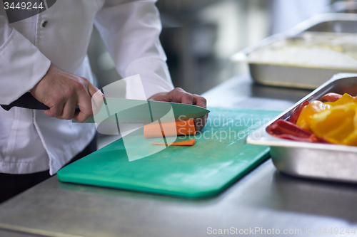 Image of chef in hotel kitchen  slice  vegetables with knife