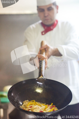 Image of chef in hotel kitchen prepare food with fire