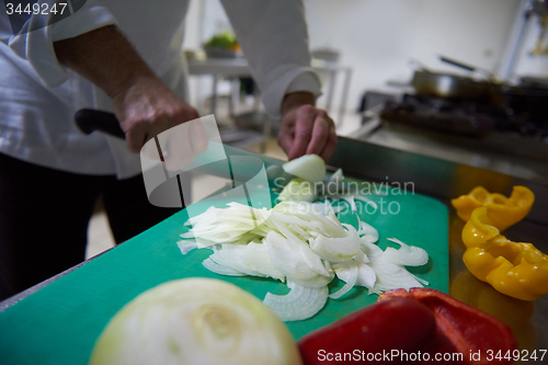 Image of chef in hotel kitchen  slice  vegetables with knife