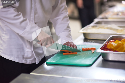 Image of chef in hotel kitchen  slice  vegetables with knife