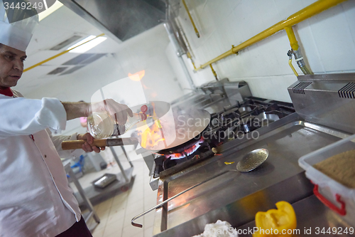 Image of chef in hotel kitchen prepare food with fire