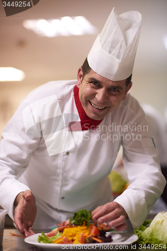 Image of chef in hotel kitchen preparing and decorating food