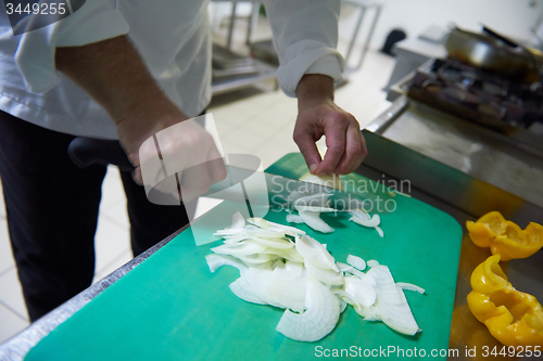 Image of chef in hotel kitchen  slice  vegetables with knife