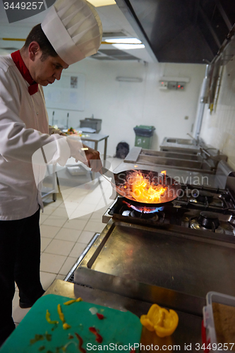 Image of chef in hotel kitchen prepare food with fire