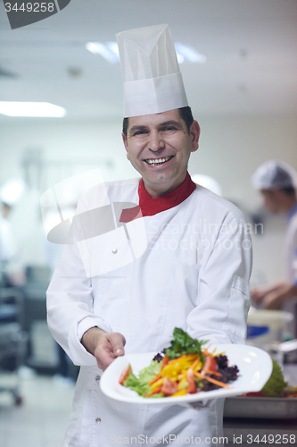 Image of chef in hotel kitchen preparing and decorating food