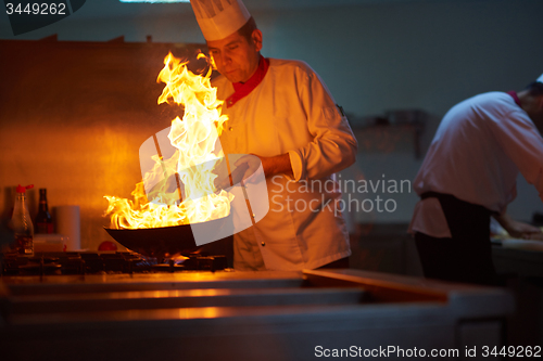 Image of chef in hotel kitchen prepare food with fire