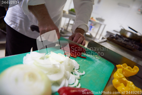 Image of chef in hotel kitchen  slice  vegetables with knife