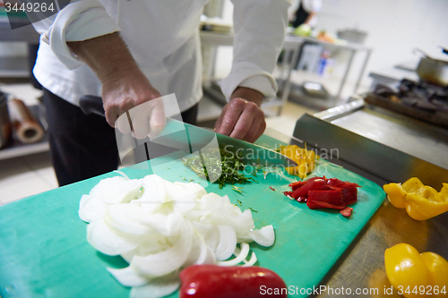 Image of chef in hotel kitchen  slice  vegetables with knife