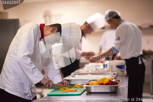 Image of chef in hotel kitchen  slice  vegetables with knife