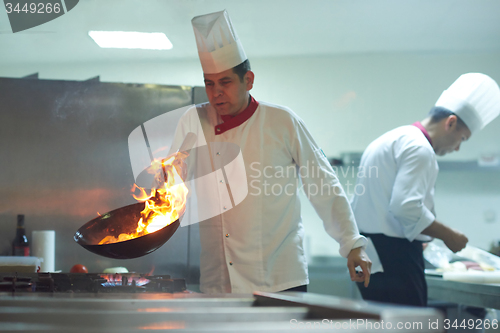 Image of chef in hotel kitchen prepare food with fire