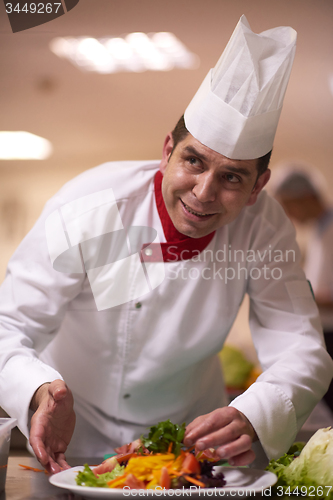 Image of chef in hotel kitchen preparing and decorating food