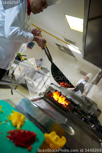 Image of chef in hotel kitchen prepare food with fire