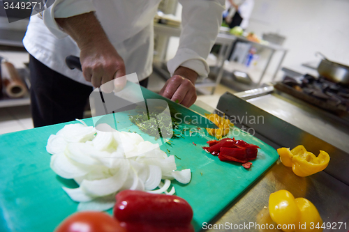 Image of chef in hotel kitchen  slice  vegetables with knife