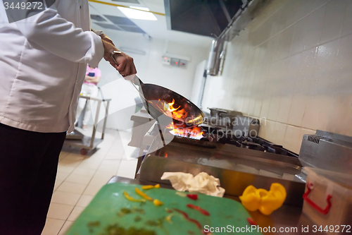 Image of chef in hotel kitchen prepare food with fire