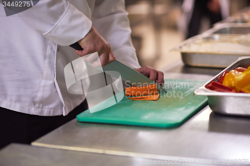 Image of chef in hotel kitchen  slice  vegetables with knife