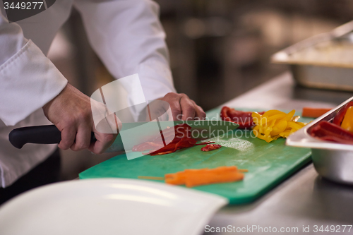 Image of chef in hotel kitchen  slice  vegetables with knife