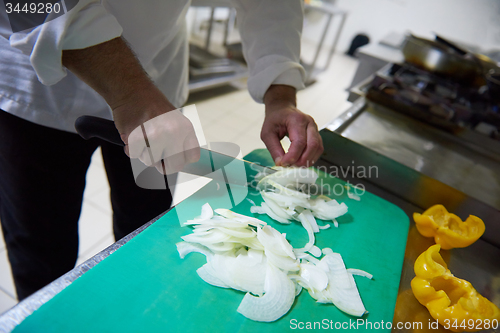 Image of chef in hotel kitchen  slice  vegetables with knife