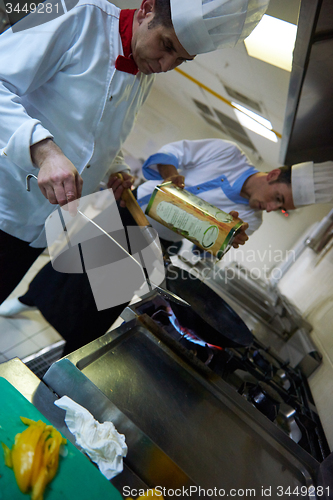 Image of chef in hotel kitchen prepare food with fire