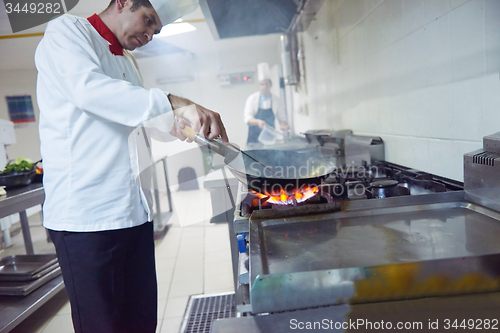 Image of chef in hotel kitchen prepare food with fire