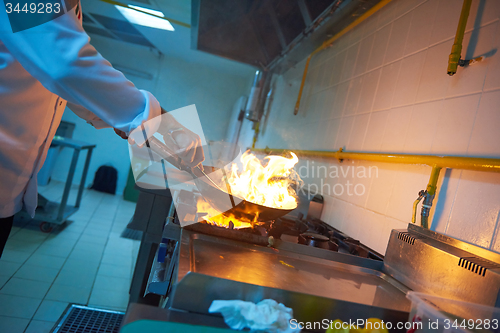 Image of chef in hotel kitchen prepare food with fire