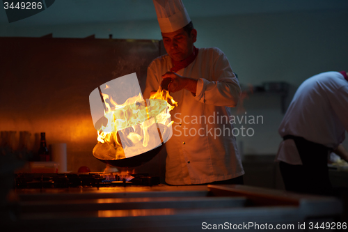 Image of chef in hotel kitchen prepare food with fire