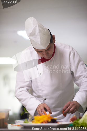 Image of chef in hotel kitchen preparing and decorating food