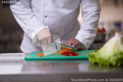 Image of chef in hotel kitchen  slice  vegetables with knife