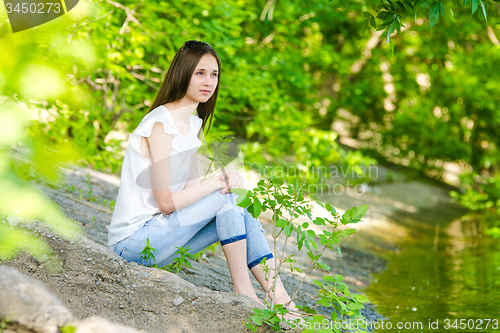 Image of A girl sits on the concrete bank of the river