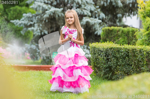 Image of Girl princess stands on the lawn in the green garden