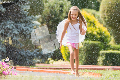 Image of Girl with angel wings running around in the rain in the garden