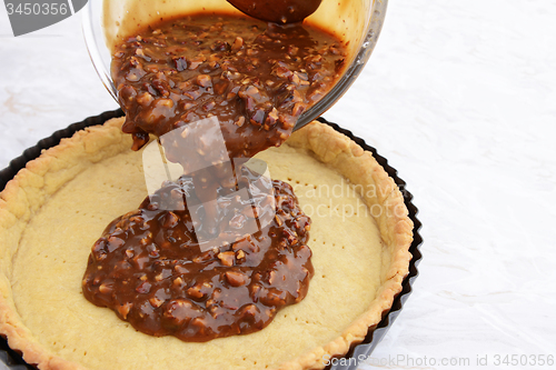 Image of Pouring pecan pie filling into a pastry case